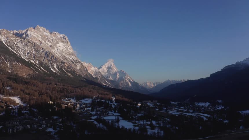 A valley town nestled between snow capped mountains under a clear blue sky