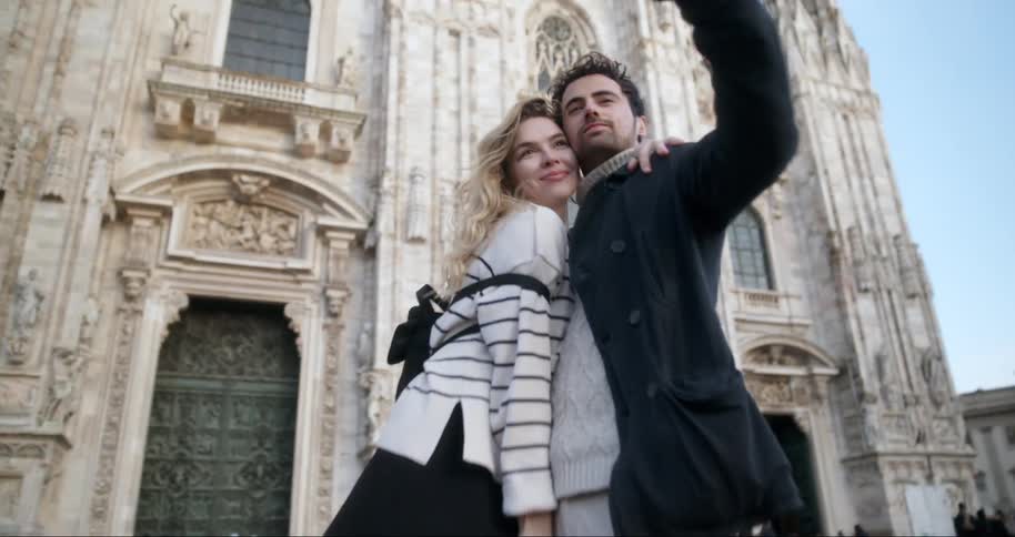 A stylish couple poses for a selfie in front of the duomo di milano