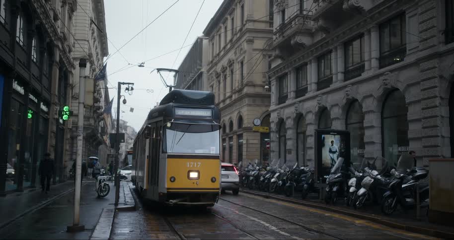 A yellow urban tram running on a street with cars passing by