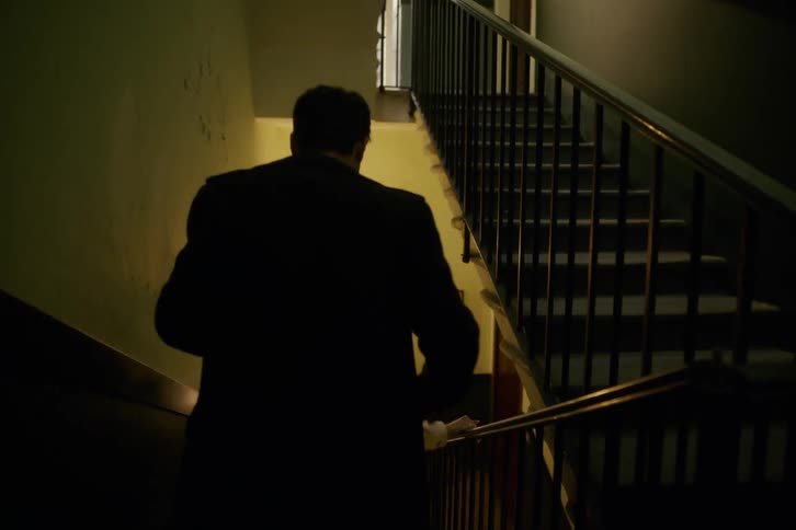 A man and woman smile as they run down a staircase