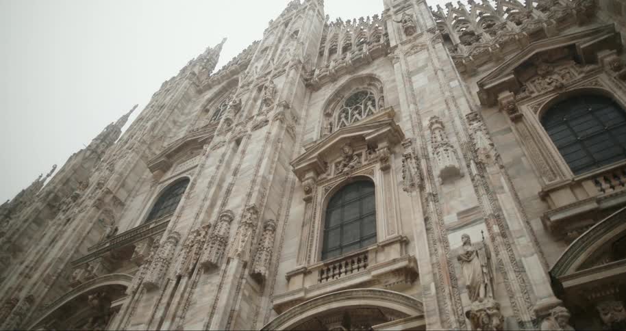 The facade of a large church of ancient architecture with huge windows and towers on the sides
