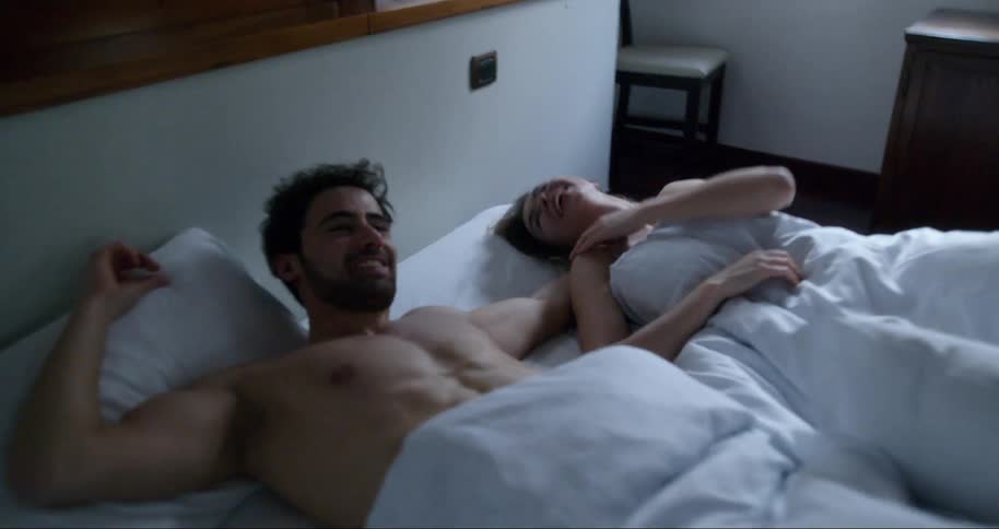 A couple lay in bed together smiling