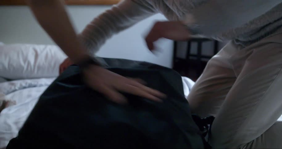 A man and woman struggle packing luggage