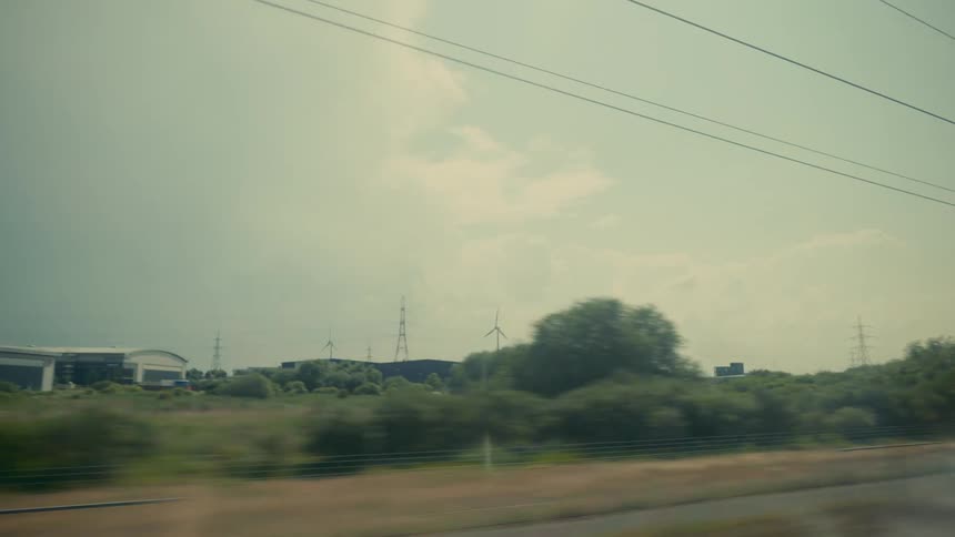 Moving view of a field with trees and scattered buildings
