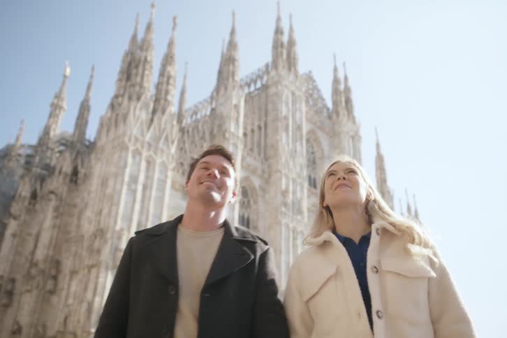 A man and woman smile as they are walking near an old gothic church
