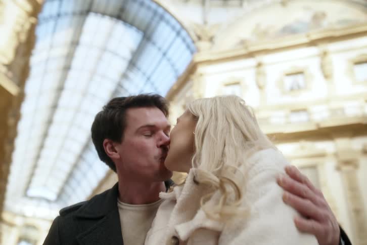 Happy couple kissing while standing inside a classic building