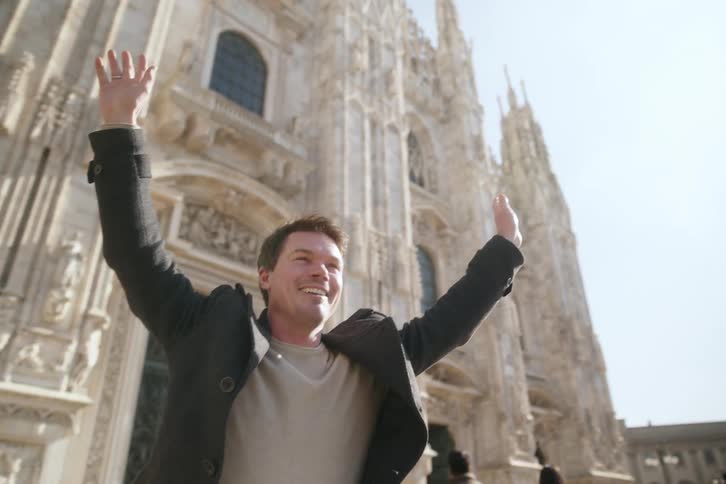 A tourist raises his arms in front of the cathedral