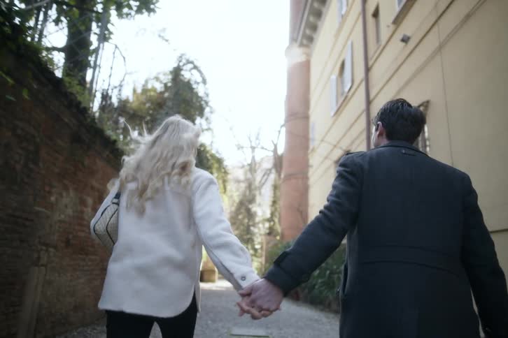 A couple hold hands while walking down the alley