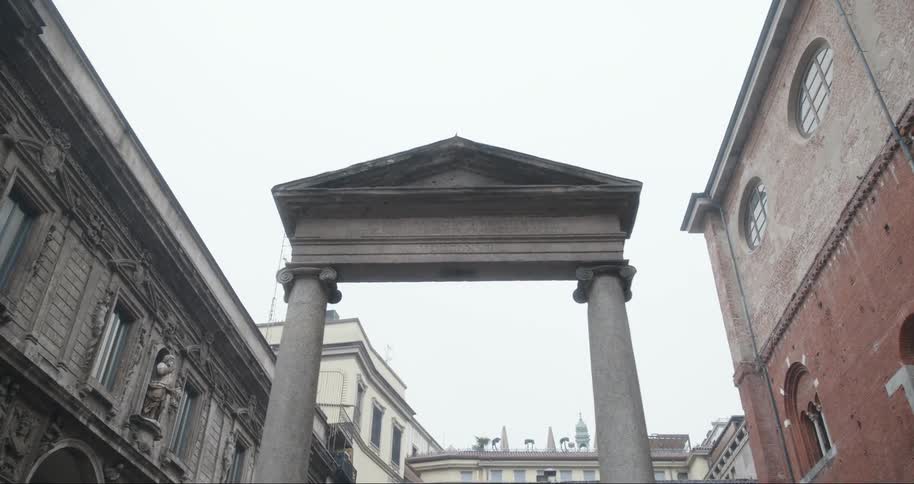 Two concrete pillars with a triangular architecture on top in the middle of a city