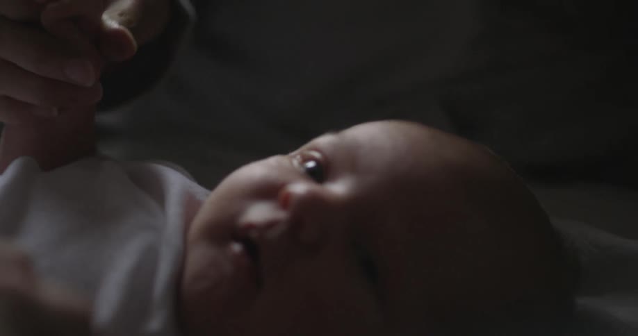 An adult holds an infant's hands