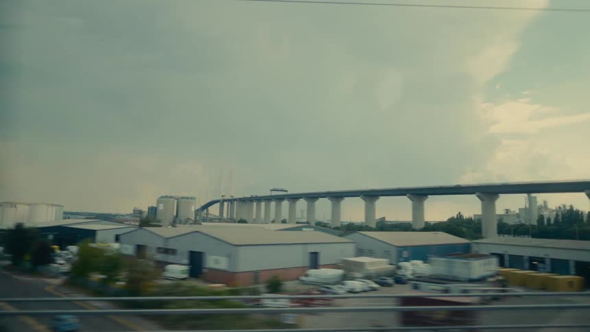A long elevated highway overlooking industrial buildings under a cloudy sky