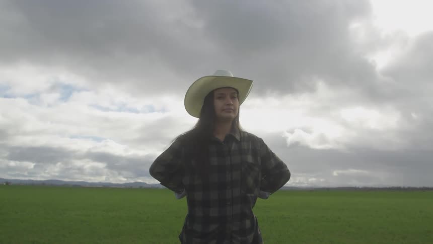 A footage of a cowgirl standing on the plain grassland