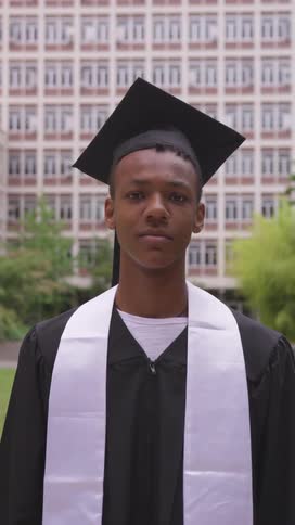 Portrait of a teenage boy wearing a graduation gown in an outdoor area