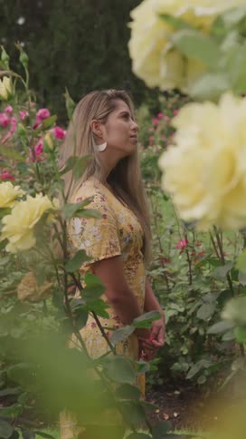 A woman is smiling as she stands in a garden full of flowers