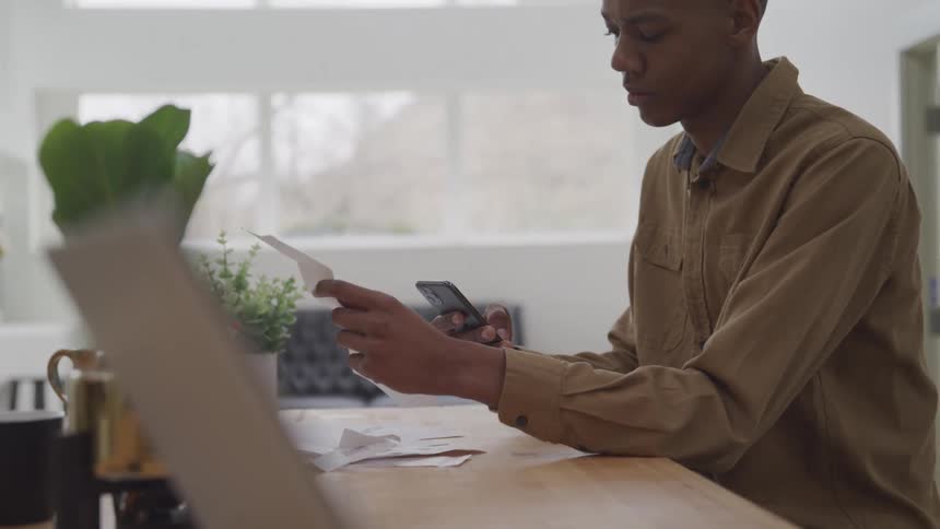 A young man is taking a receipt and taking a picture with his cell phone