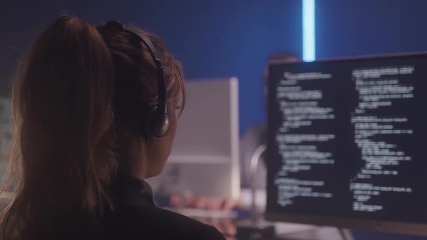 A womans head with a ponytail and wearing a headset and is looking at a computer with the screen full of white texts