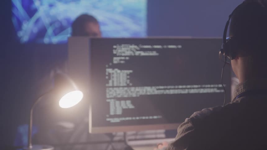 People working at desks in a dimly lit room focused on computers a call center or tech support setting