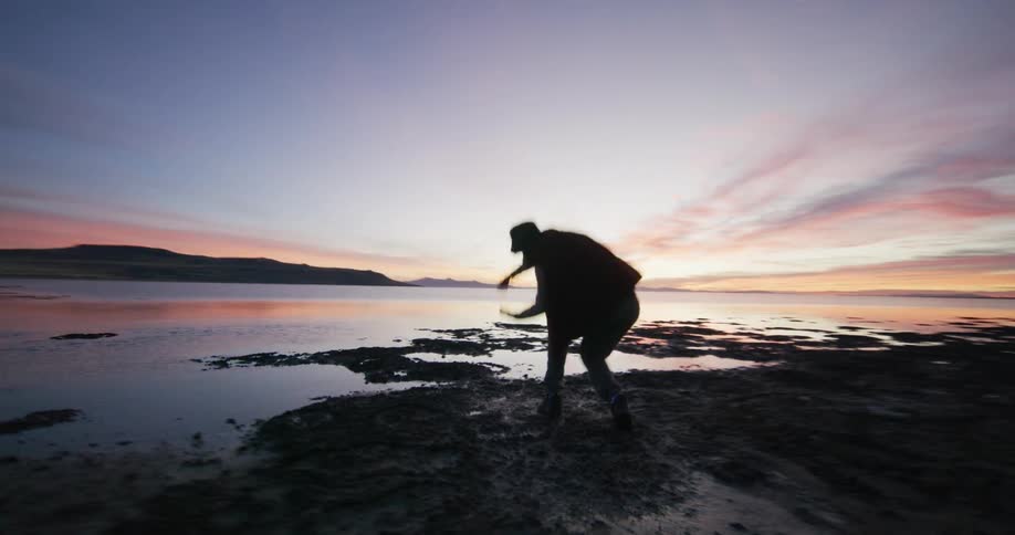 A man is dancing by the shore of the lake