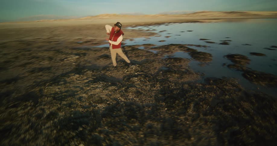 Man dancing on rocks by a lake at sunrise