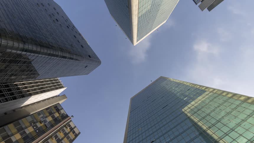 The upward view of several tall buildings against a blue sky with scattered clouds
