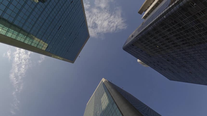 Three tall buildings are viewed from below angled against a clear blue sky
