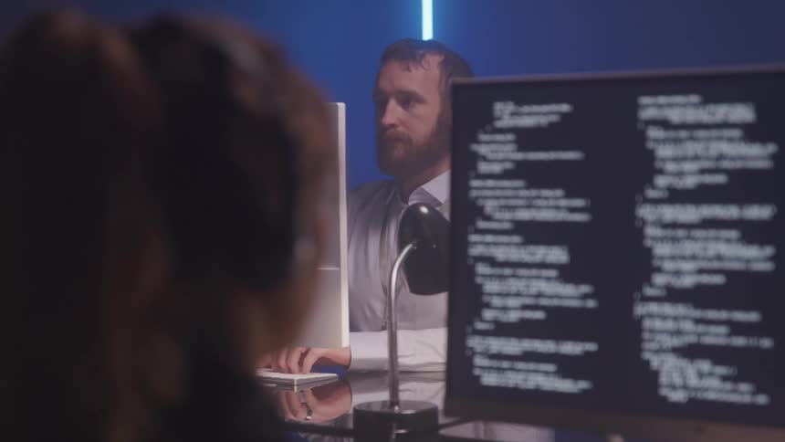 Man and woman sitting at a table working in front of a computer with data