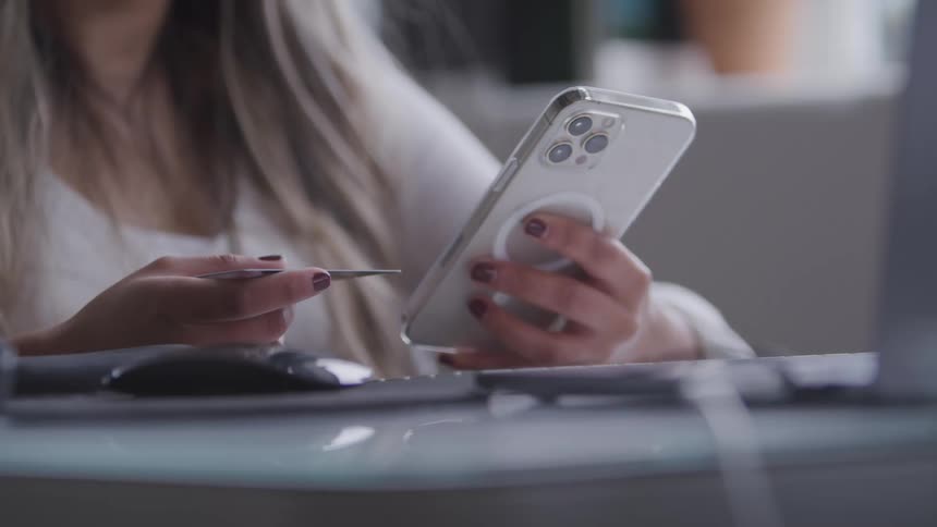 A woman is using her cell phone with one hand