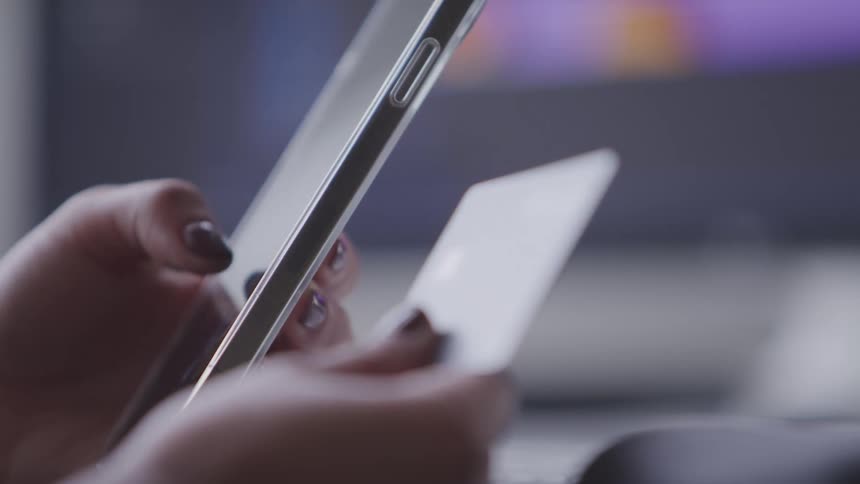 A closeup shows hands holding a smartphone and a credit card an online transaction or mobile payment
