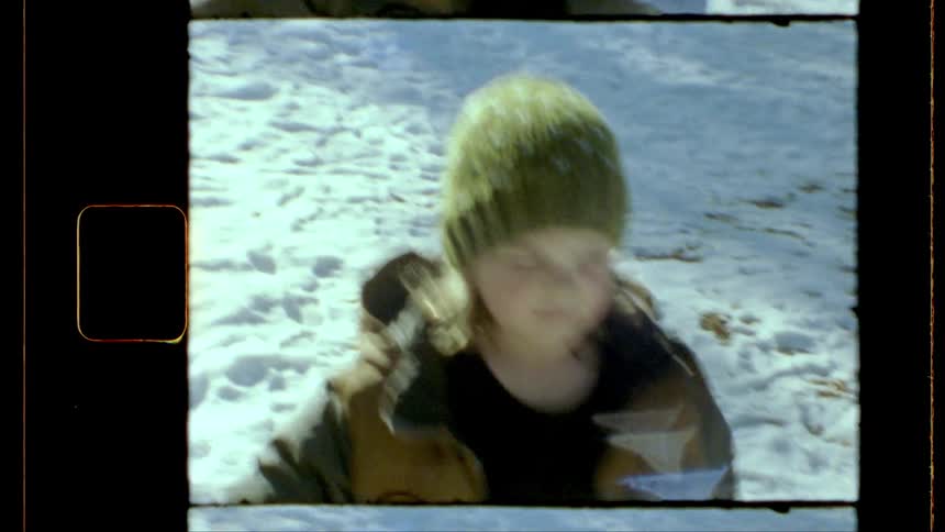 A vintagestyle shot shows a young person wearing a green knit hat and a jacket in a snowy outdoor environment