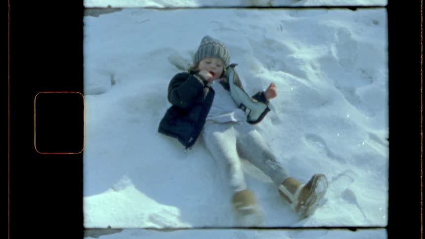 A girl is doing snow angels outside