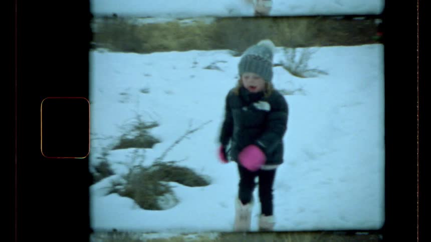 A little girl wearing winter clothes runs in a snowcovered lawn