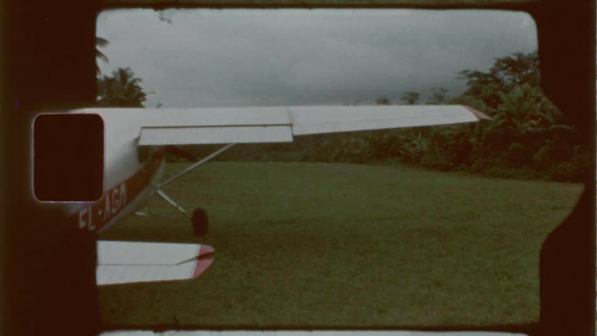 A small single engine plane parked in a grass field