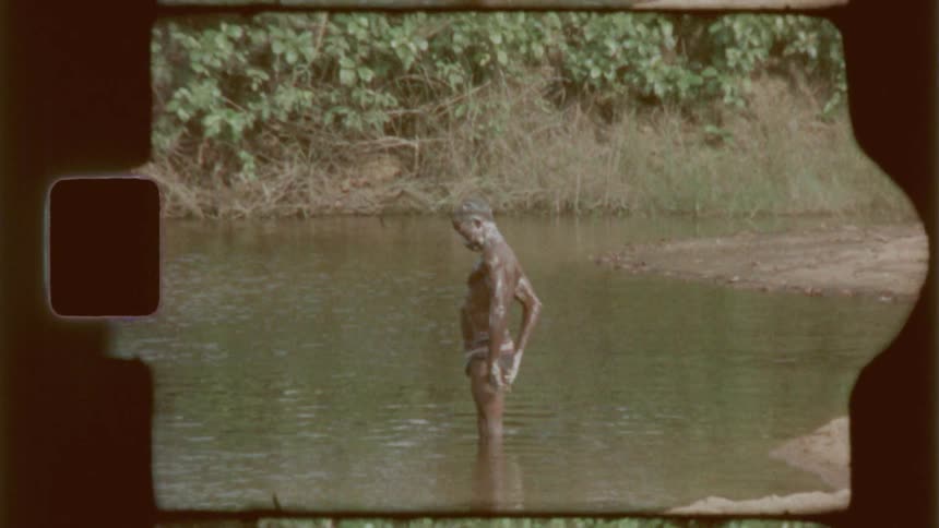 A vintage style shot of a person taking a bath on the shallow water of a river