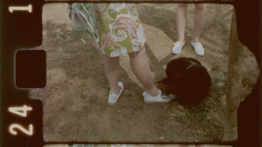 A woman stands outside as a monkey is trying to tie her shoes