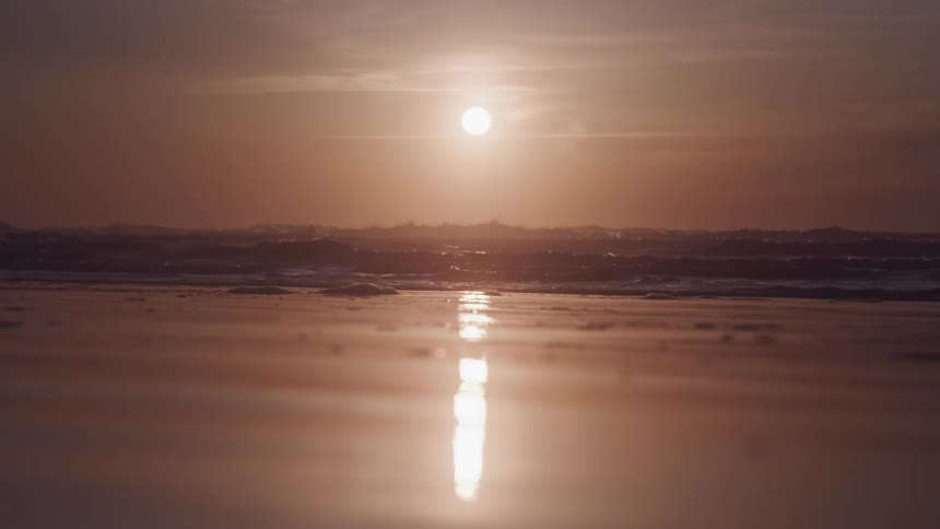 Landscape of a calm sea with the reddish sun on the horizon