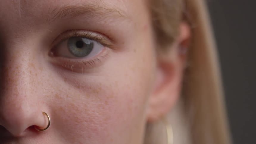 Partial closeup of a blonde womans face with blue eyes