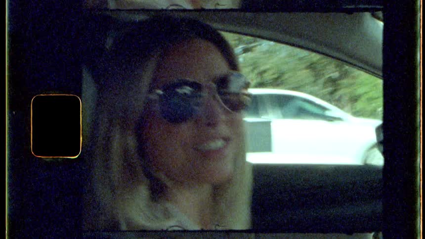 A woman is smiling and talking as she drives on a highway in traffic