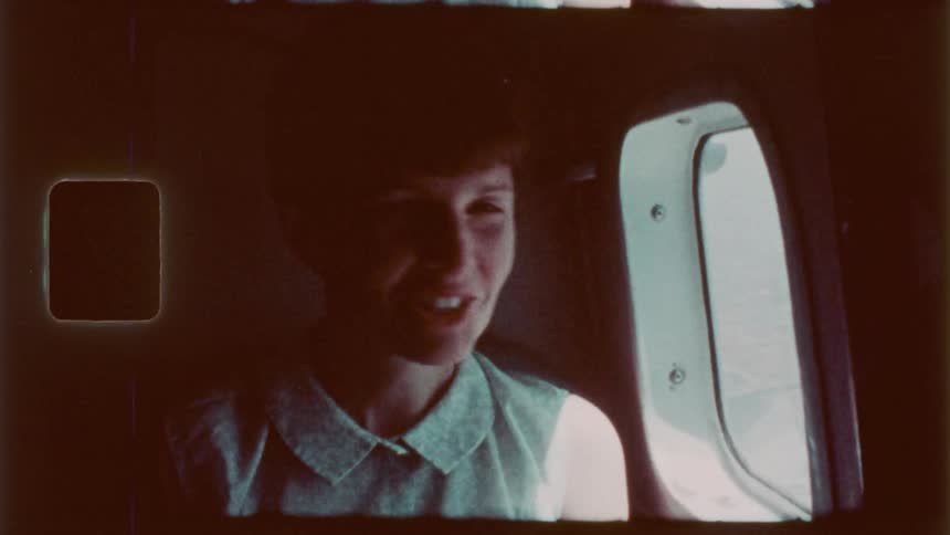 A woman waves while looking out the plane window