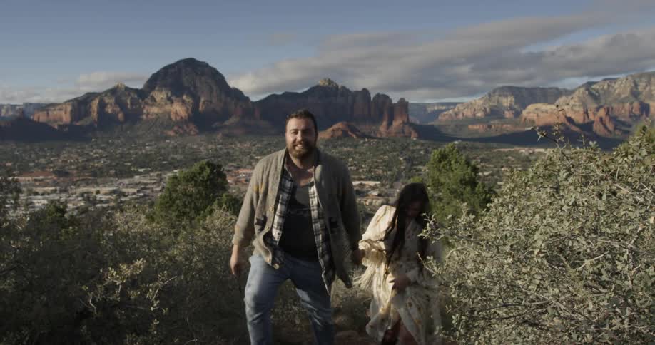 Man and woman holding hands walking up a trail