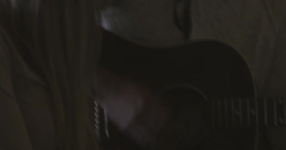 A man plays a guitar while he and a woman sing