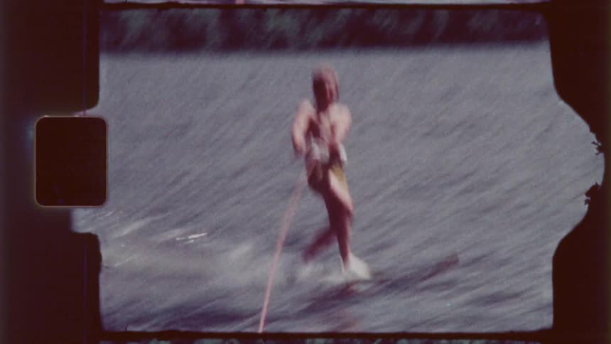 Woman water skiing on a lake holding onto the rope as she glides across the water