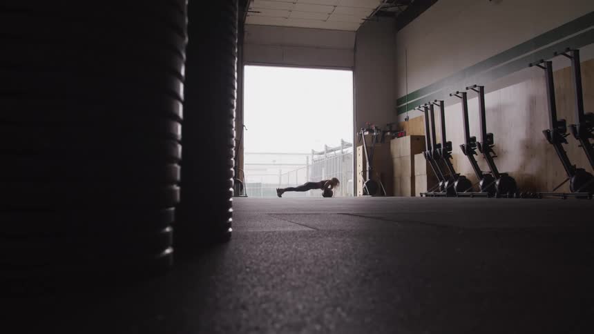 A woman is doing push ups in the gym
