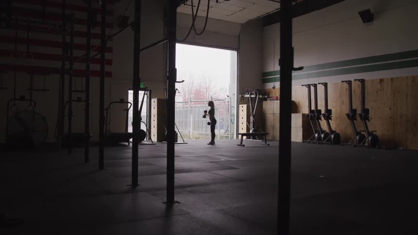 Woman is lifting weights by herself in a large gym