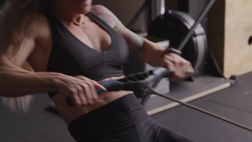A muscular woman exercises on a rowing machine