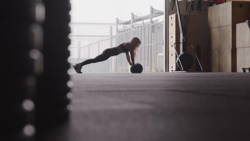 Woman doing pushups on a weighted bar on the mat