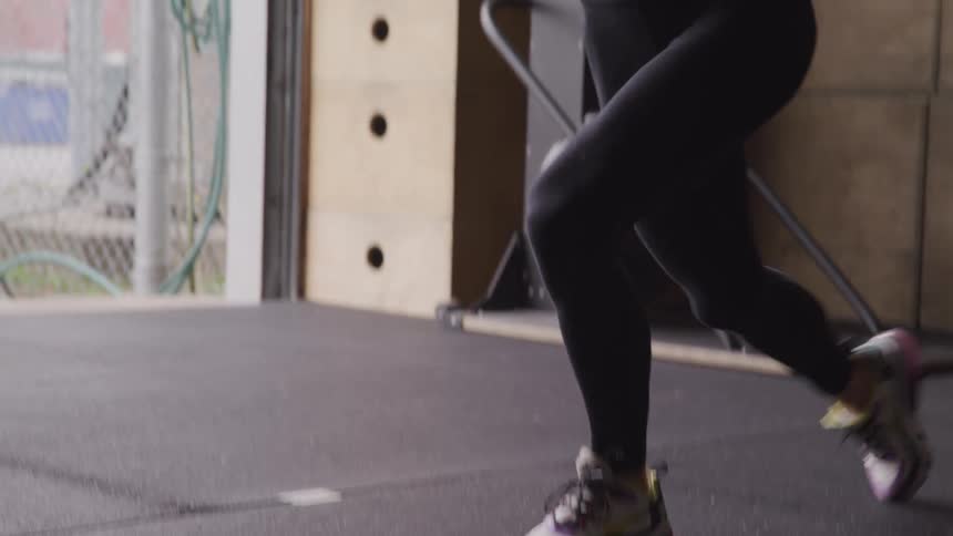 Woman performing lunge squats while holding a weight plate in a gym