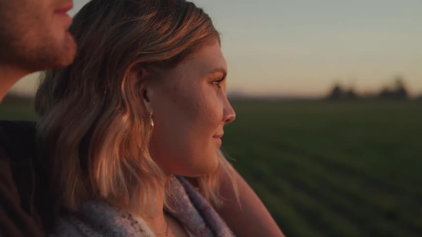 Woman observing the horizon at dusk with a man by her side