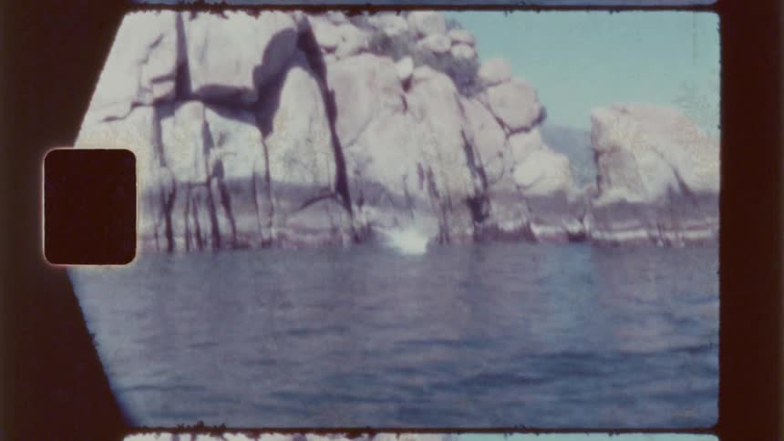 Person jumping off a rocky cliff into the ocean