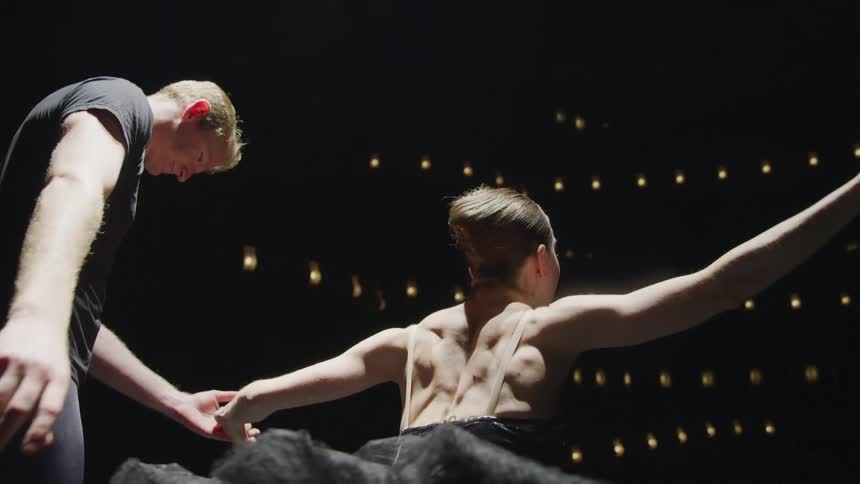 A male and a female ballet dancer bow to the audience while performing on stage