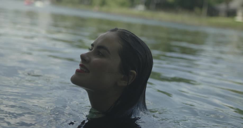 A woman swimming in a body of water and smiling